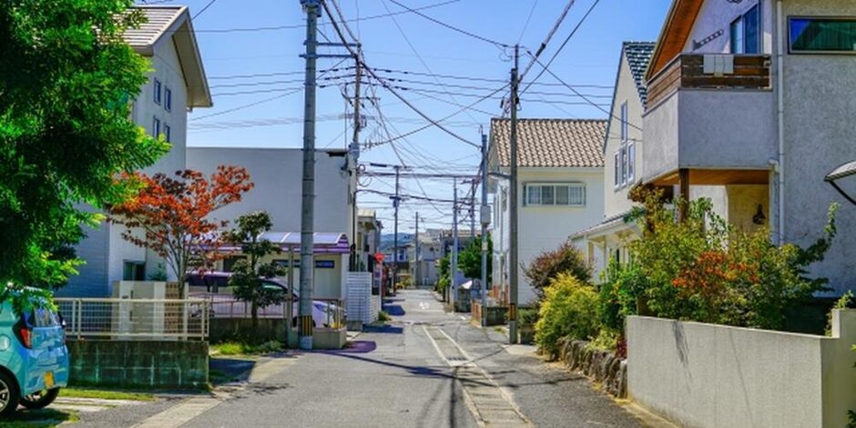 電柱と電線が立ち並ぶ住宅街の路地、晴れた空のもとで静かな住宅環境を表現したイメージ