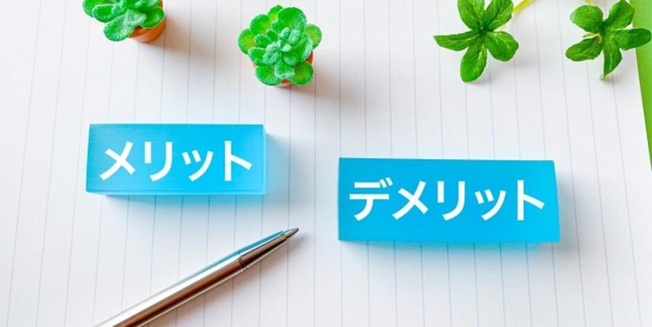 ノートの上に並べられた「メリット」と「デメリット」のカード、ペンと観葉植物が添えられた比較・検討のイメージ