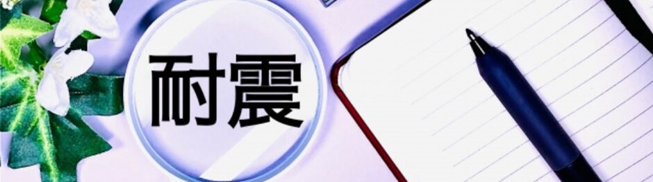 「耐震」の文字が書かれた虫眼鏡とノート・ペンが並ぶ、防災や耐震対策をイメージしたデスク上の写真
