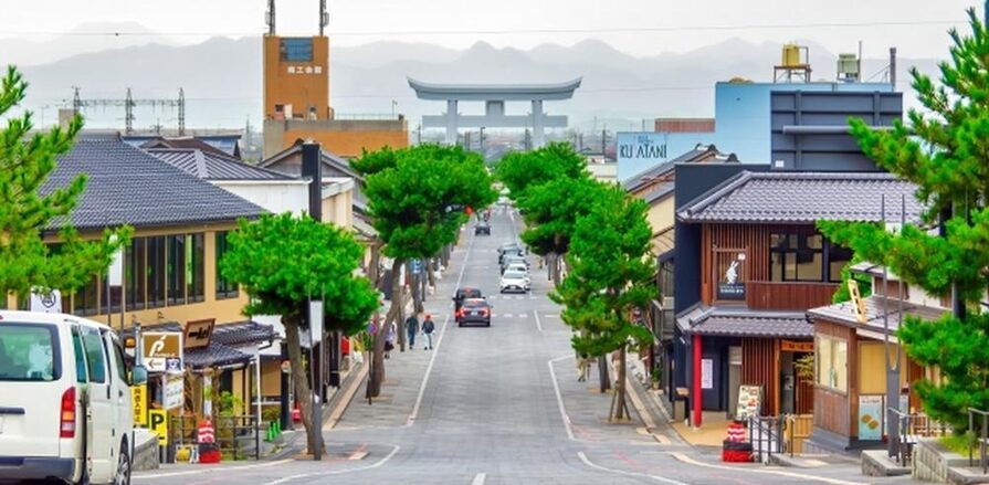 歴史的な街並みの中心にある参道。両側には和風建築の店が並び、奥には大きな鳥居が見える。
