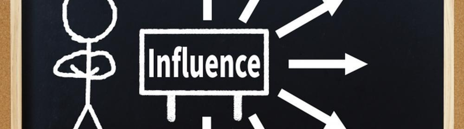黒板に描かれた棒人間と“Influence”の文字、そこから放射状に広がる矢印が、影響力の拡がりを示している図解イメージ