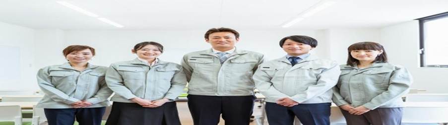 作業服を着た社員たちが並んで微笑む集合写真：チームワークや職場の一体感を表すイメージ