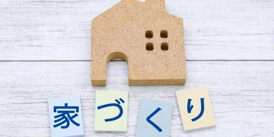 木製の家の模型と「家づくり」と書かれた文字カードが並べられた、注文住宅のイメージを表す写真。