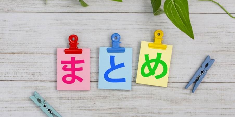 カラフルなクリップで留められた「まとめ」の文字カードと観葉植物のイメージ