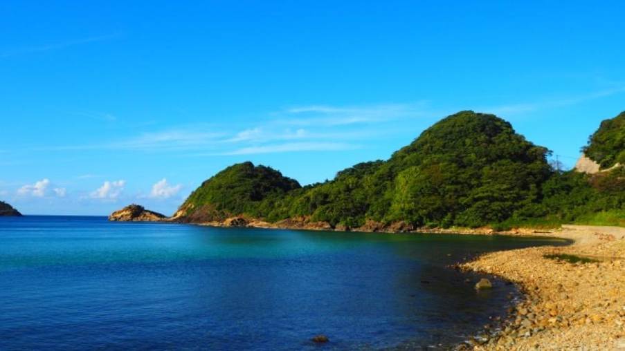青空とエメラルドグリーンの海に囲まれた静かな入り江の風景