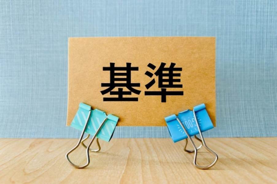「基準」と書かれたクラフト紙が青いクリップで立てかけられているイメージ