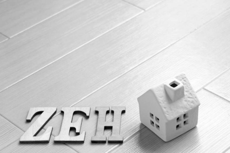 白い床の上に並ぶ「ZEH」の文字と家のオブジェ、シンプルなZEHのイメージ
